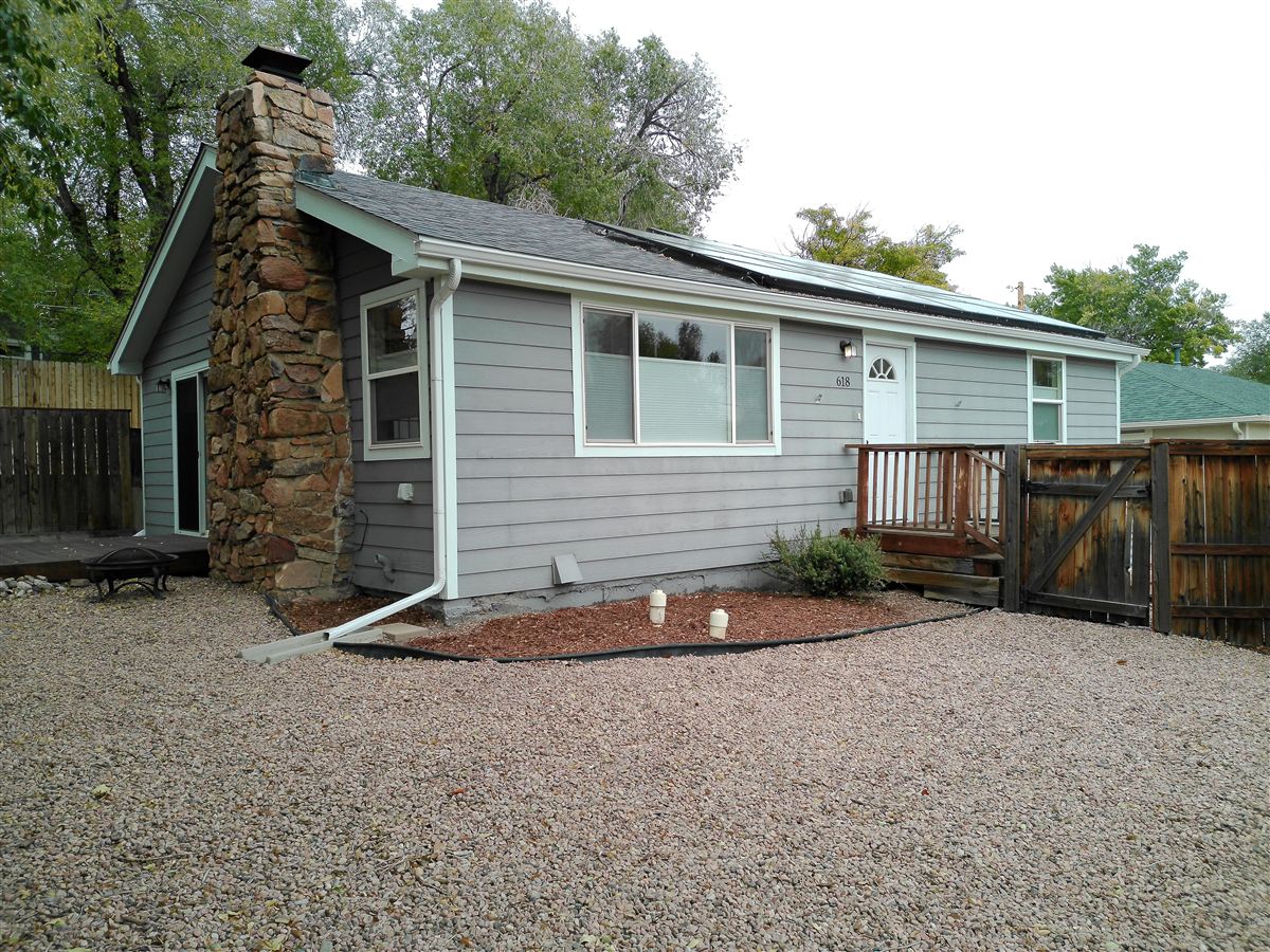 Back of the home with stone chimney and deck
